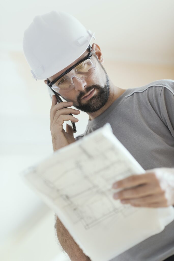 Professional construction worker checking a project and calling
